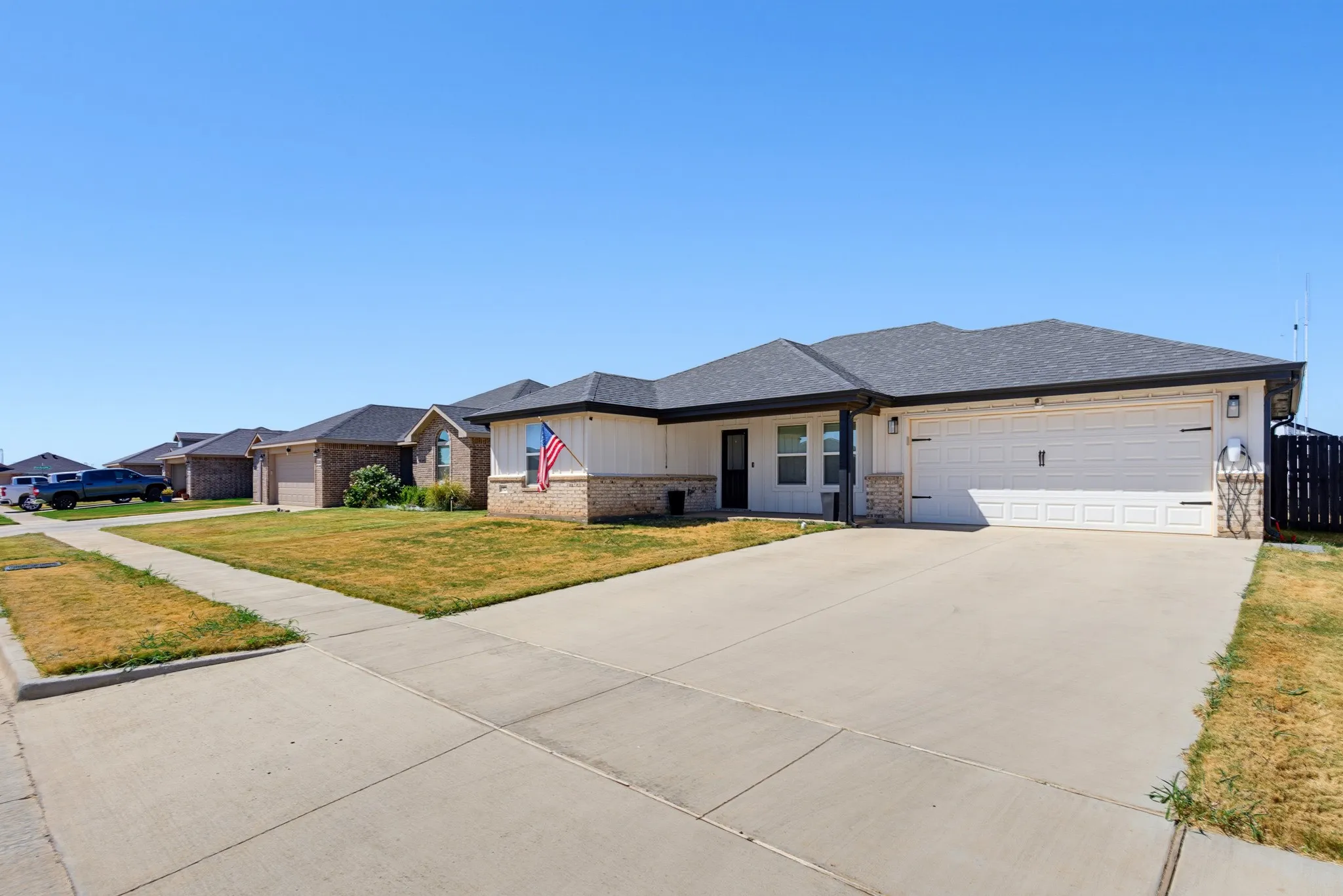 Ranch-style exterior with a dark shingle roof, brick and vertical siding facade, and an attached two-car garage