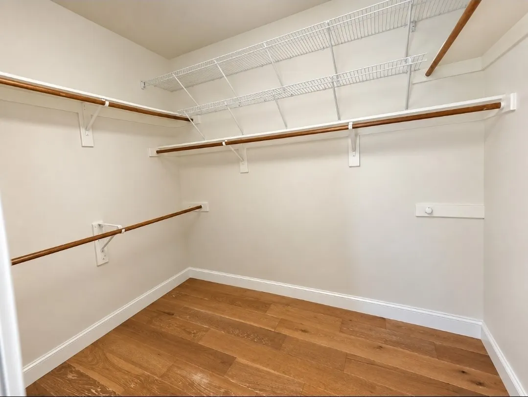 Walk-in closet with wood-finish flooring, multiple hanging rods, and wire shelving