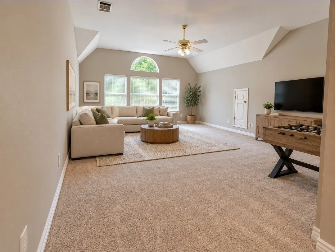Vaulted ceiling with a ceiling fan, arched window, wall-to-wall carpeting, and wood-finish cabinetry