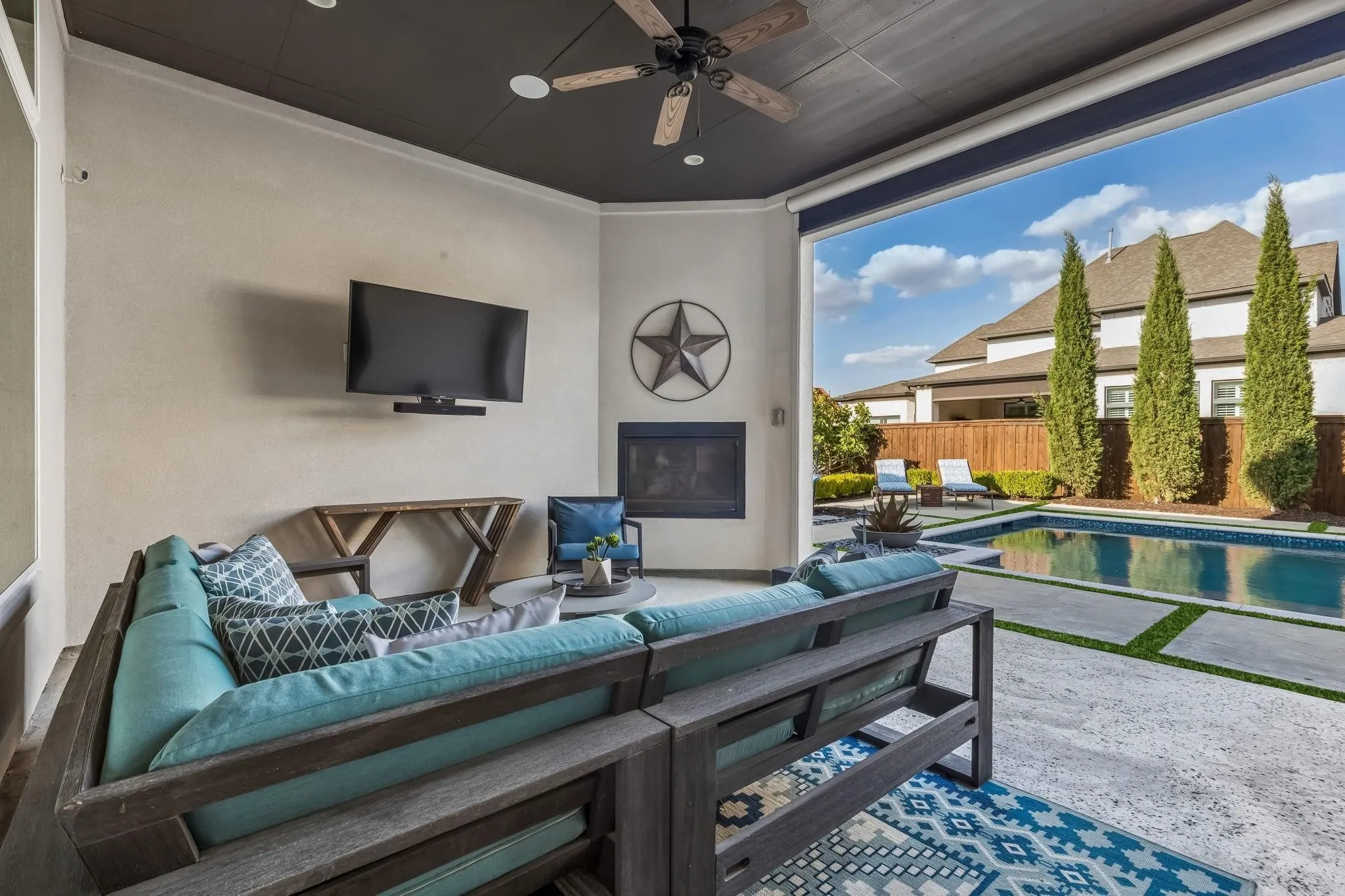 Covered outdoor living area with a fireplace and electric retractable screens for year-round comfort and entertaining.