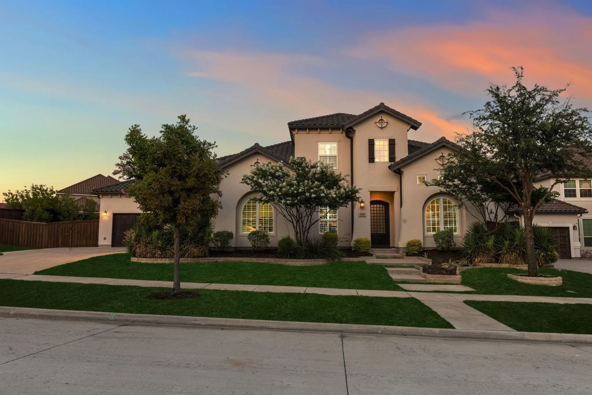 Stucco exterior with a tiled roof, arched windows, and dark wood shutters