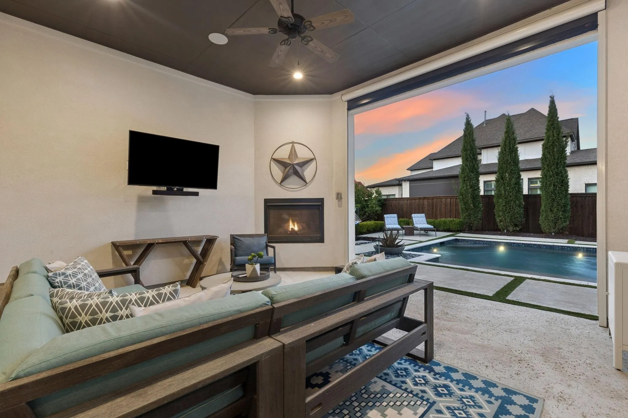 Covered outdoor living area with a built-in fireplace, ceiling fan, and recessed lighting
