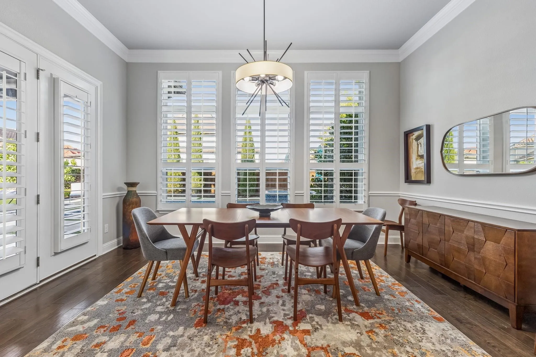 Dining area featuring plantation shutters, overlooking the resort-style pool and seamlessly connecting to the covered outdoor living area.