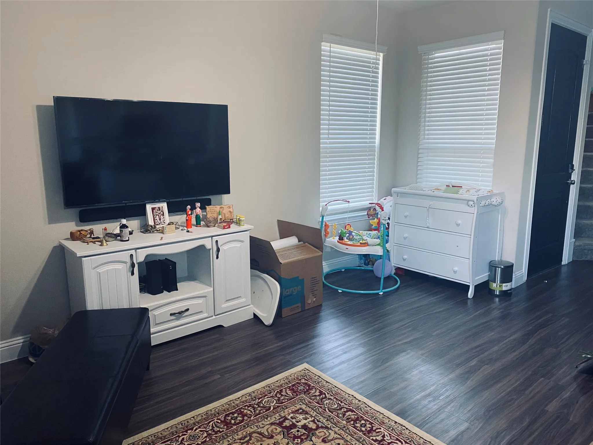 Living area featuring dark wood-style flooring and baseboards