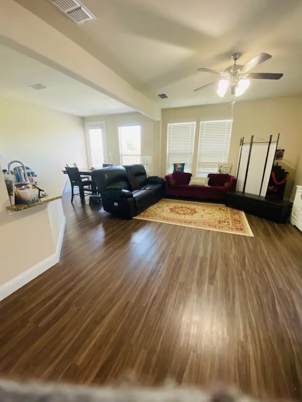 Living room with dark wood-type flooring and ceiling fan