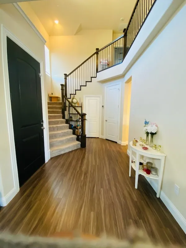 Entryway featuring a towering ceiling, stairs, and wood finished floors