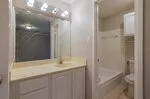 Vanity with a light-toned countertop, a built-in sink, and a large wall-mounted mirror