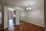 Hardwood flooring, decorative wall paneling, crown molding, double doors, and a ceiling-mounted light fixture