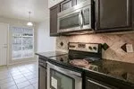 Kitchen featuring stainless steel appliances, dark wood cabinetry, solid surface countertops, and a decorative tile backsplash