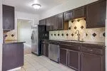 Kitchen featuring dark wood cabinetry, solid surface countertops, patterned tile backsplash, stainless steel appliances, and tile flooring