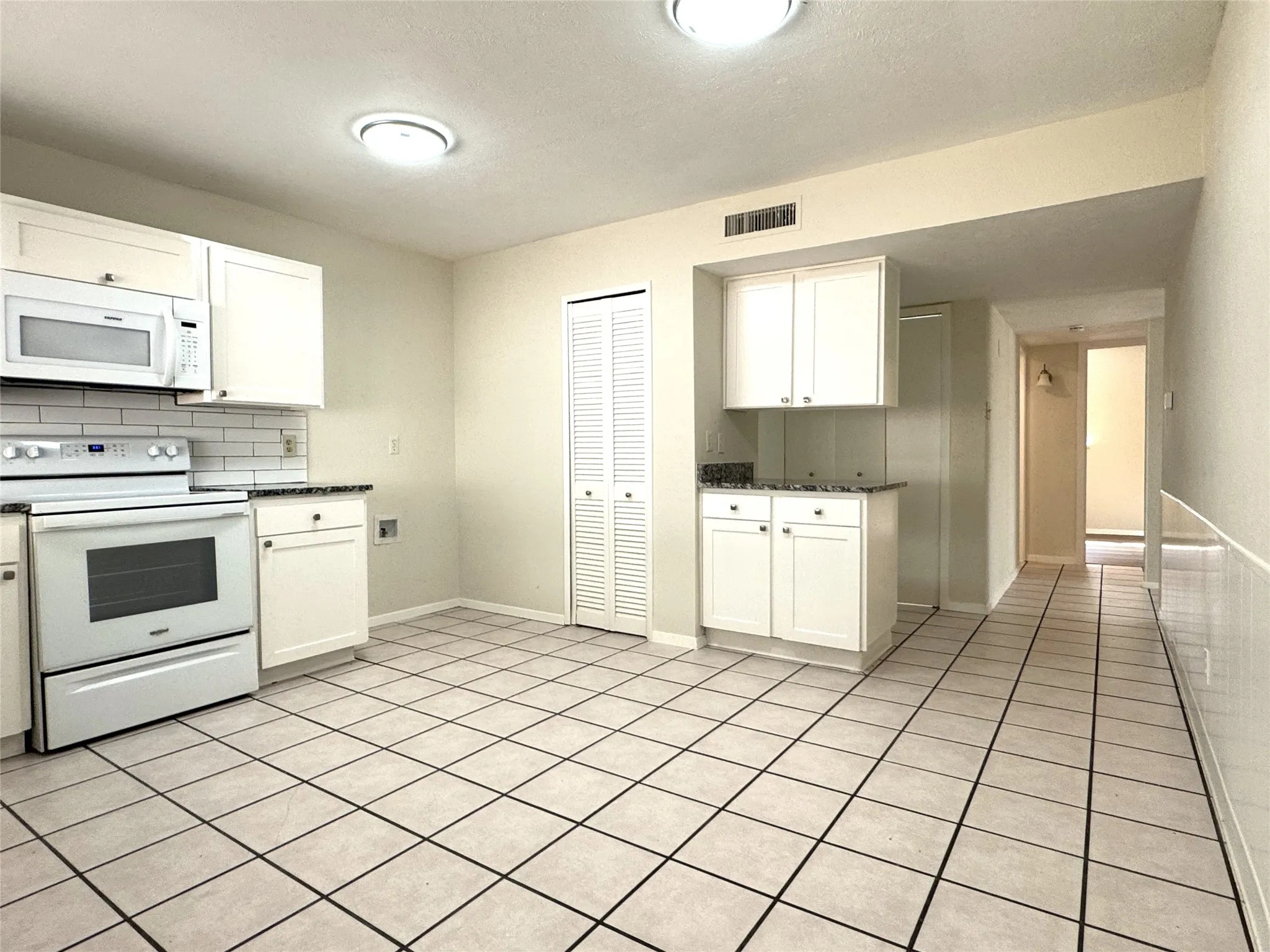 Spacious kitchen boasts granite countertops and white subway tile backsplash