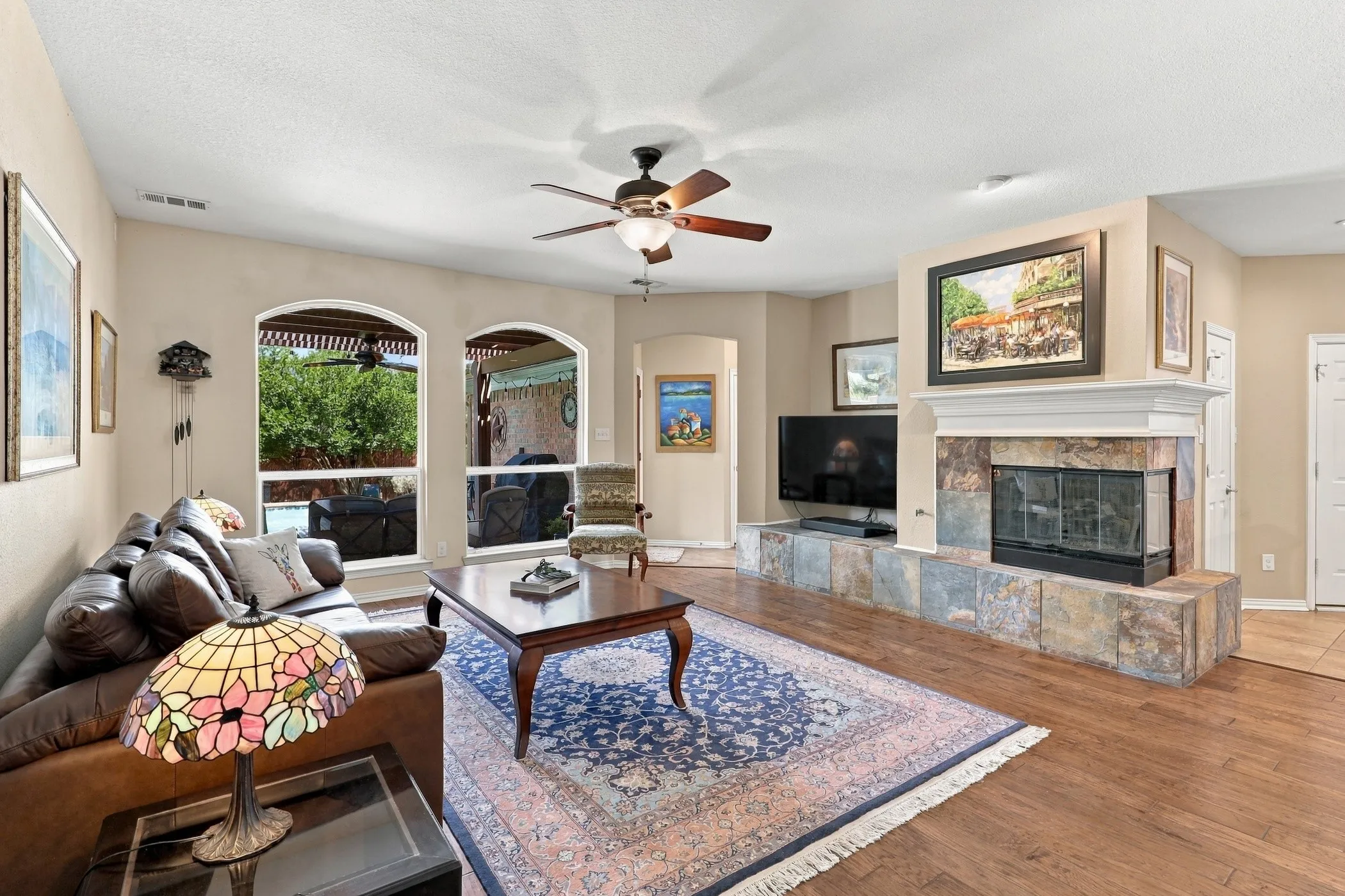 Living area featuring wood-finish flooring, an ornate fireplace with a stone surround and hearth, and arched windows