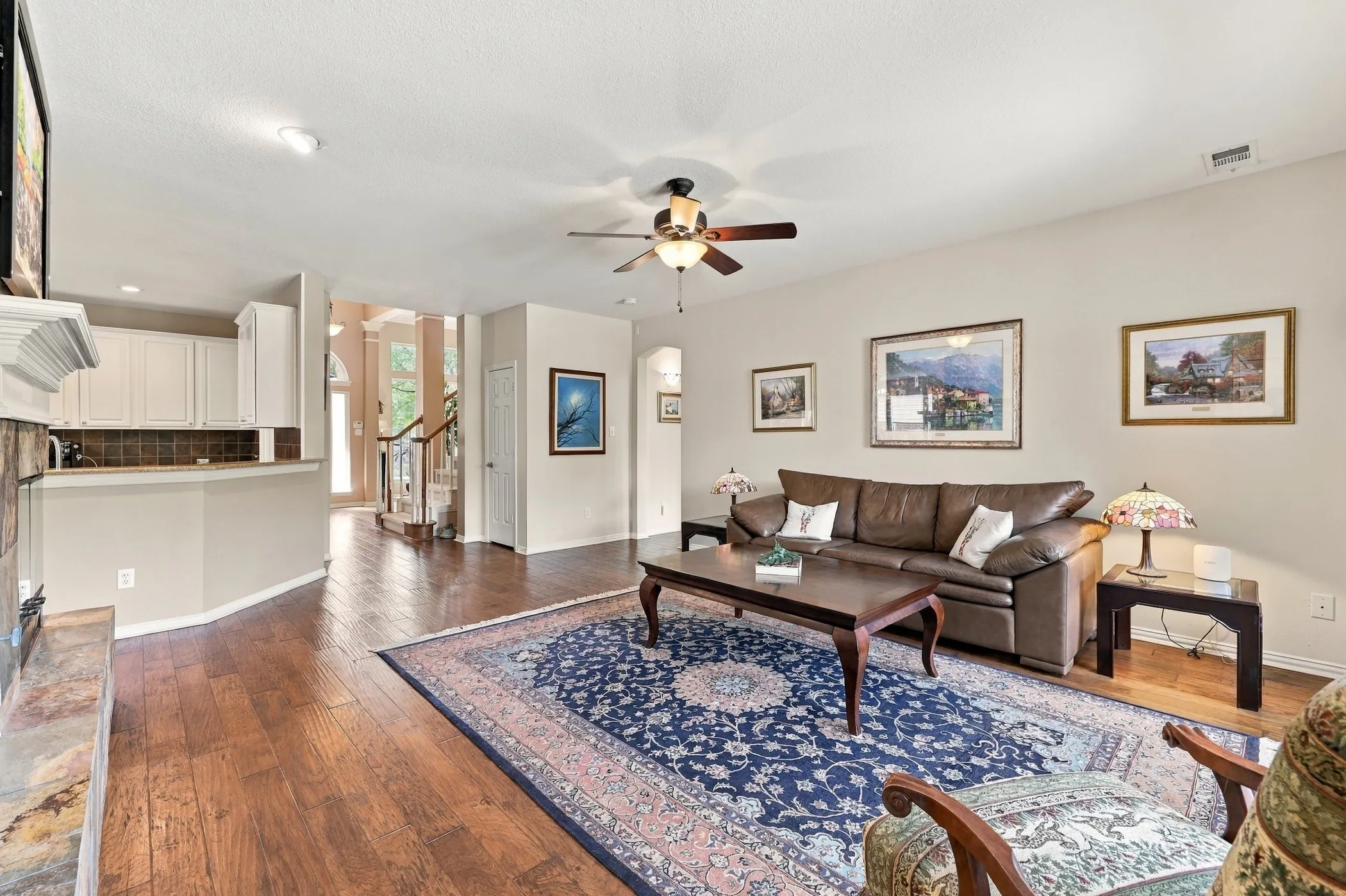 Open floorplan.  Wood-finish flooring throughout, ceiling fan with light fixture, and white cabinetry