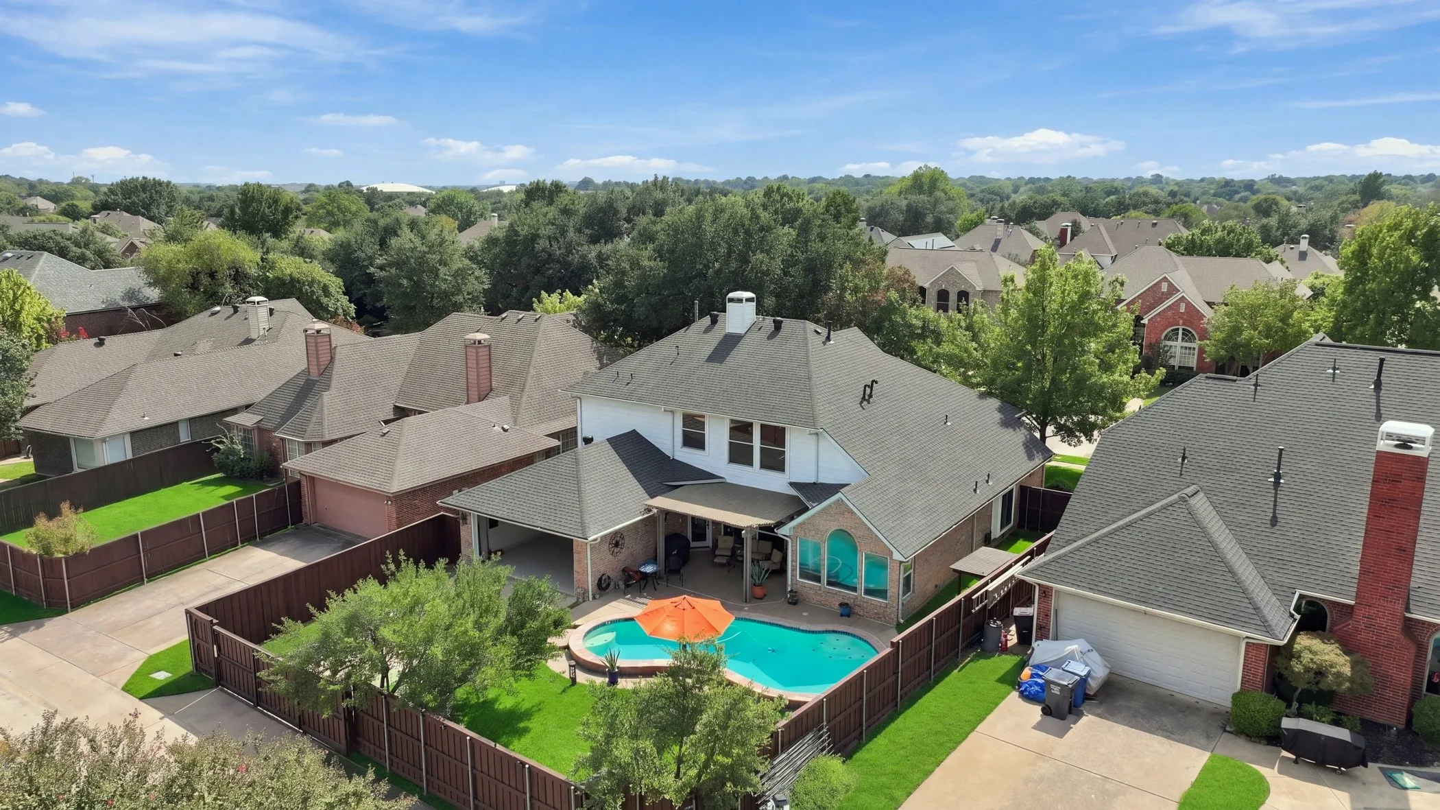 Private backyard enclosed by electric driveway gate featuring a swimming pool, covered patio, and manicured lawn