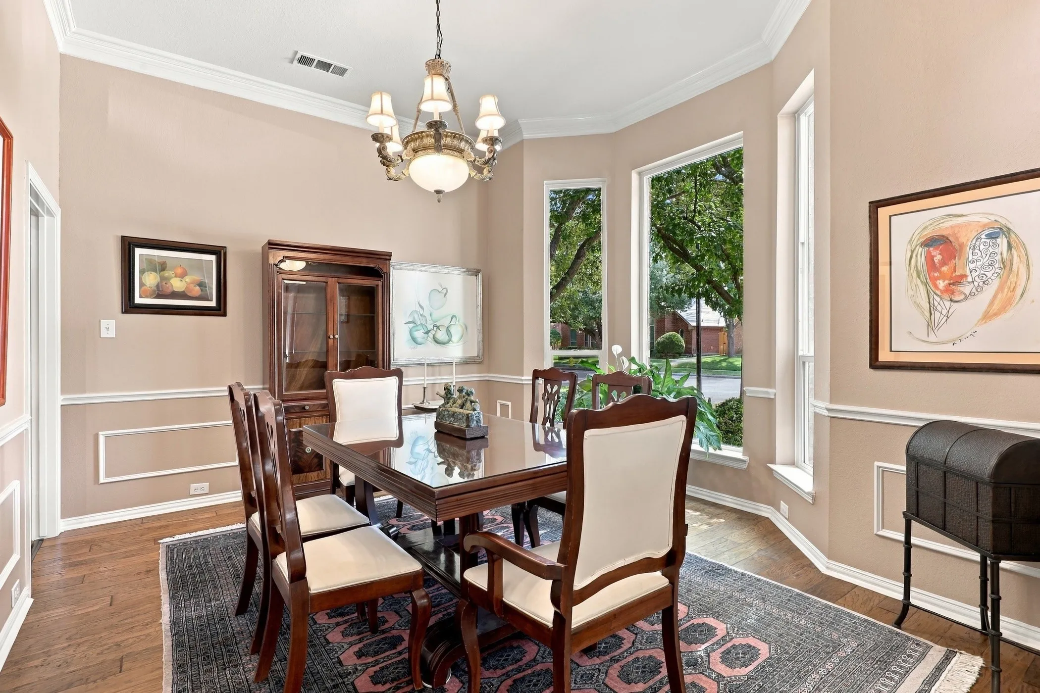 Formal dining room with bay window, wood floors, crown molding, and wainscoting.