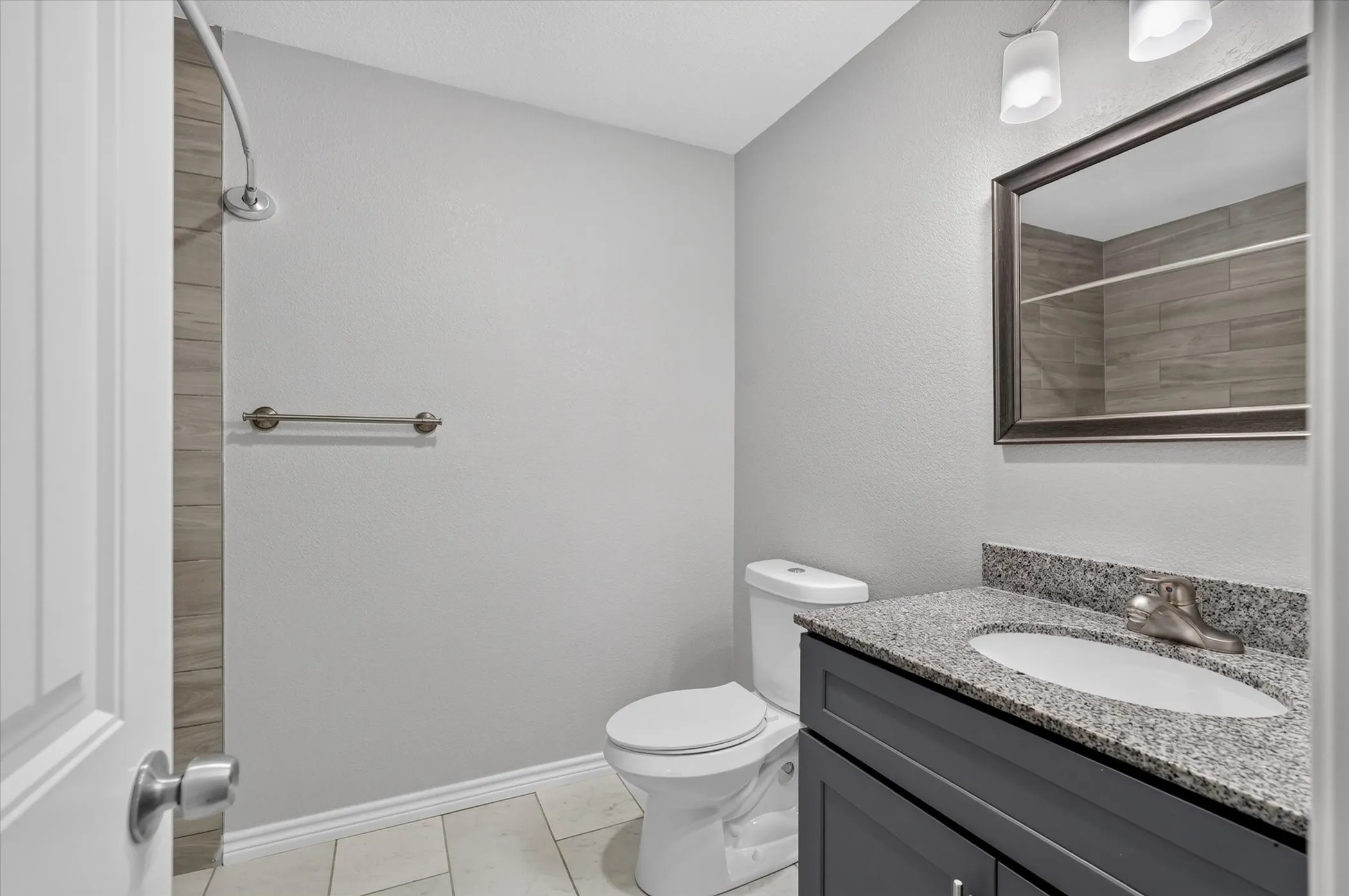 Hallway bathroom featuring a vanity with a granite countertop, undermount sink, and dark cabinetry