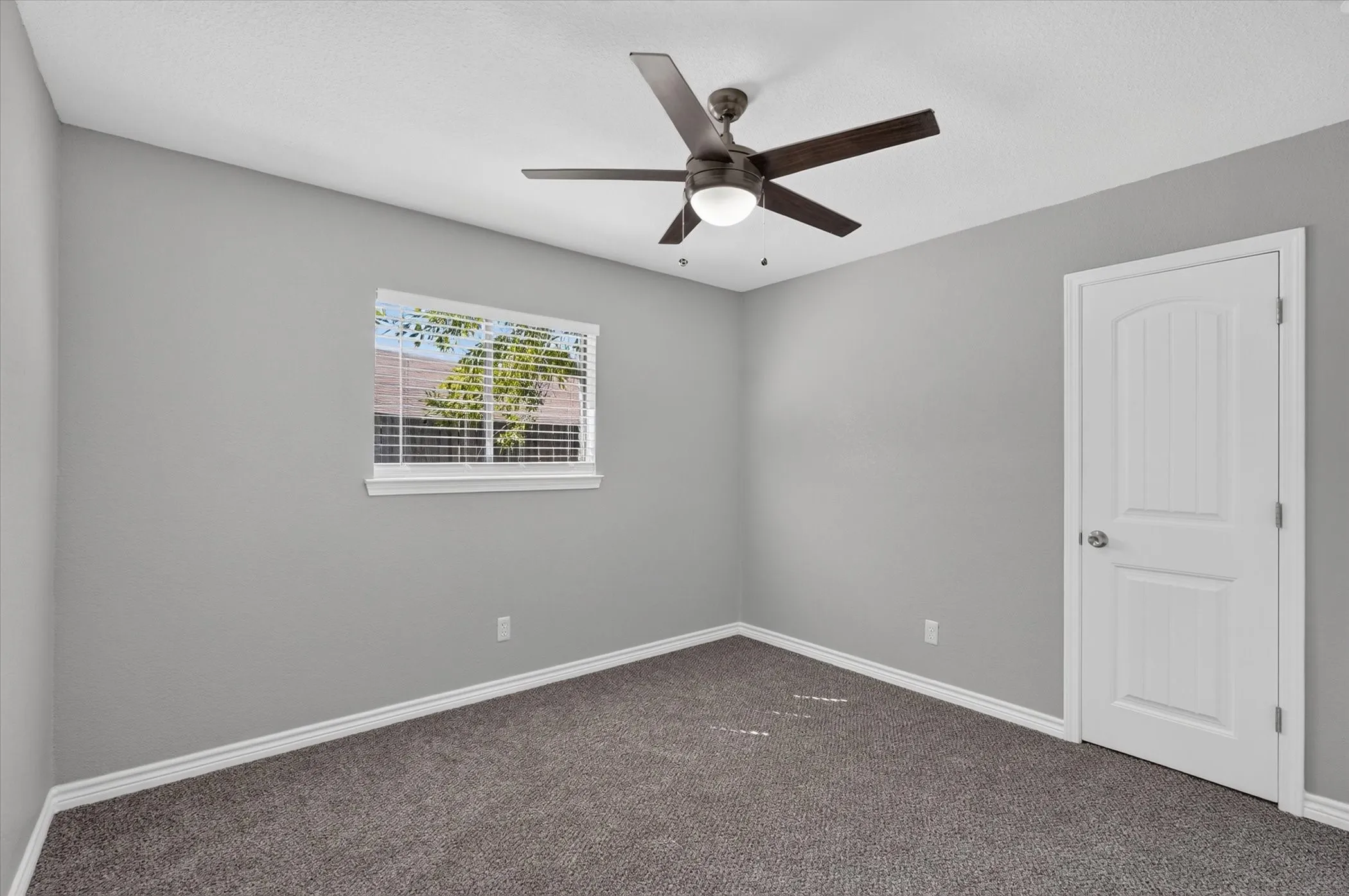 Neutral wall paint, ceiling fan, carpet flooring, window with blinds, and white trim