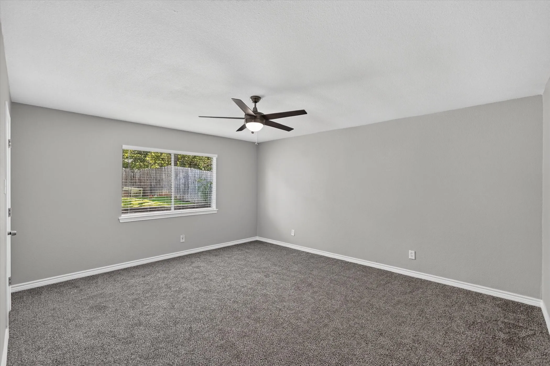 Large primary bedroom with walk in closet and linen closet along with ensuite. Neutral wall paint, ceiling fan, carpet flooring, window with blinds, and white trim