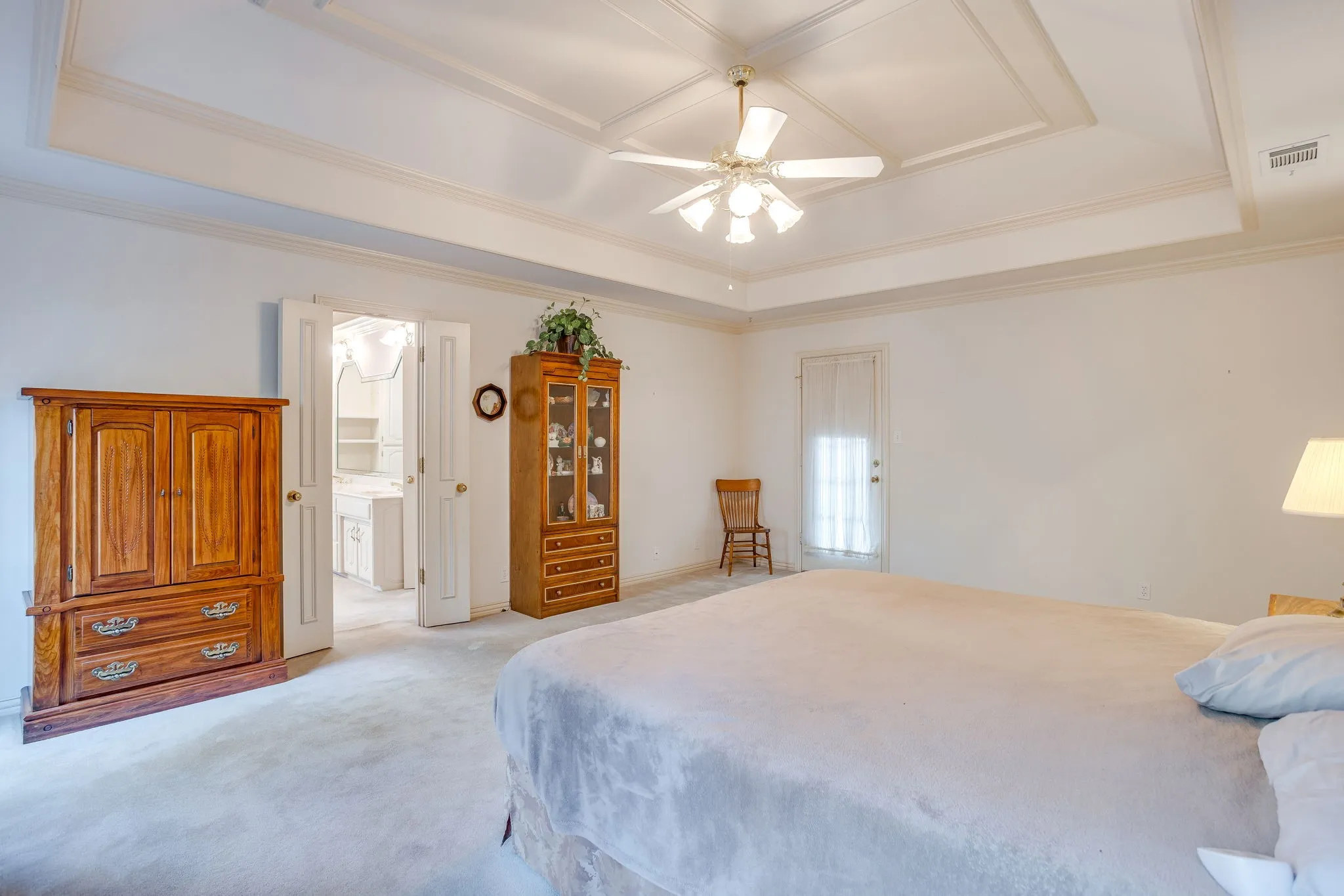 Tray ceiling with crown molding, ceiling fan with integrated lighting, double doors, and a door leading to the exterior