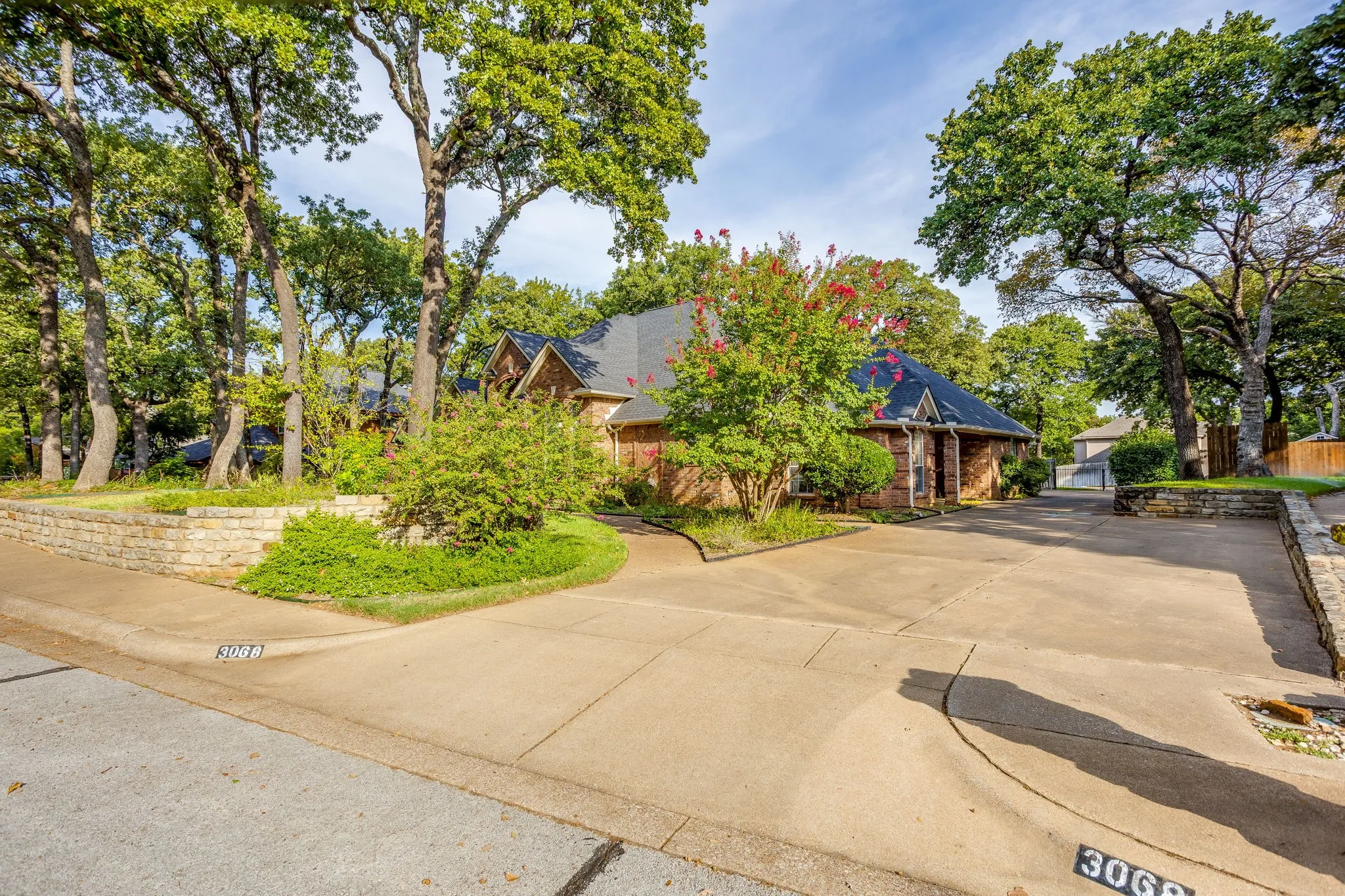 Brick exterior with a dark roof and mature trees