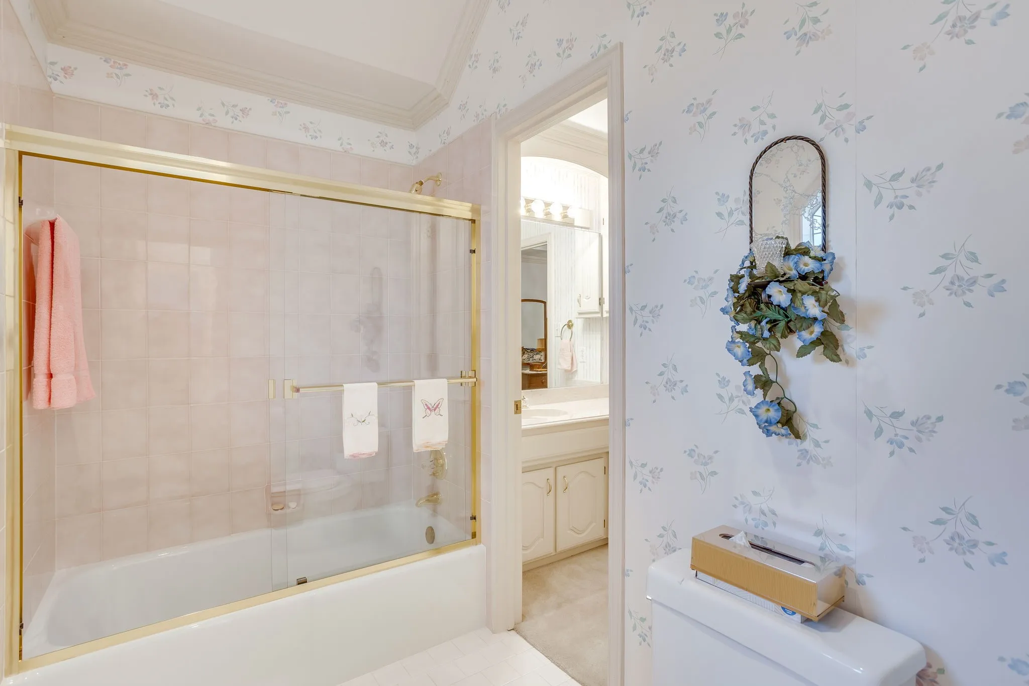 Bathtub with gold-tone framed glass enclosure and integrated towel bar