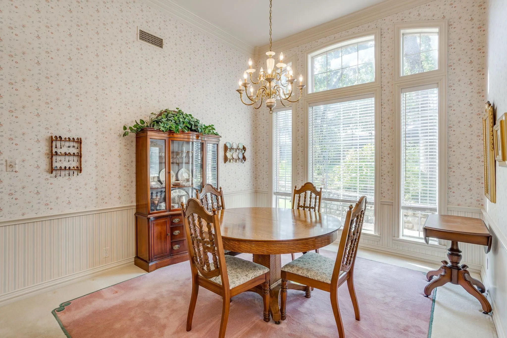 Floor-to-ceiling windows, arched window details, chandelier lighting, beadboard wainscoting, and patterned wallpaper