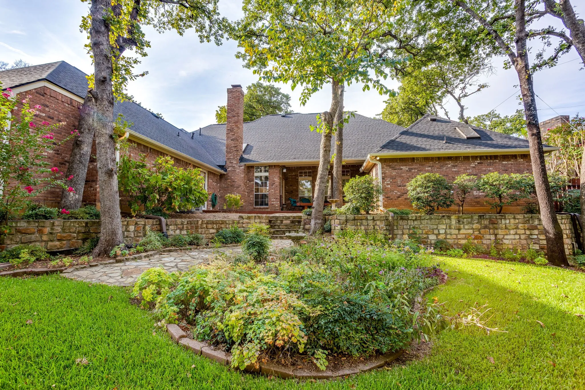 Expansive backyard featuring a manicured lawn, established landscaping, and a flagstone pathway