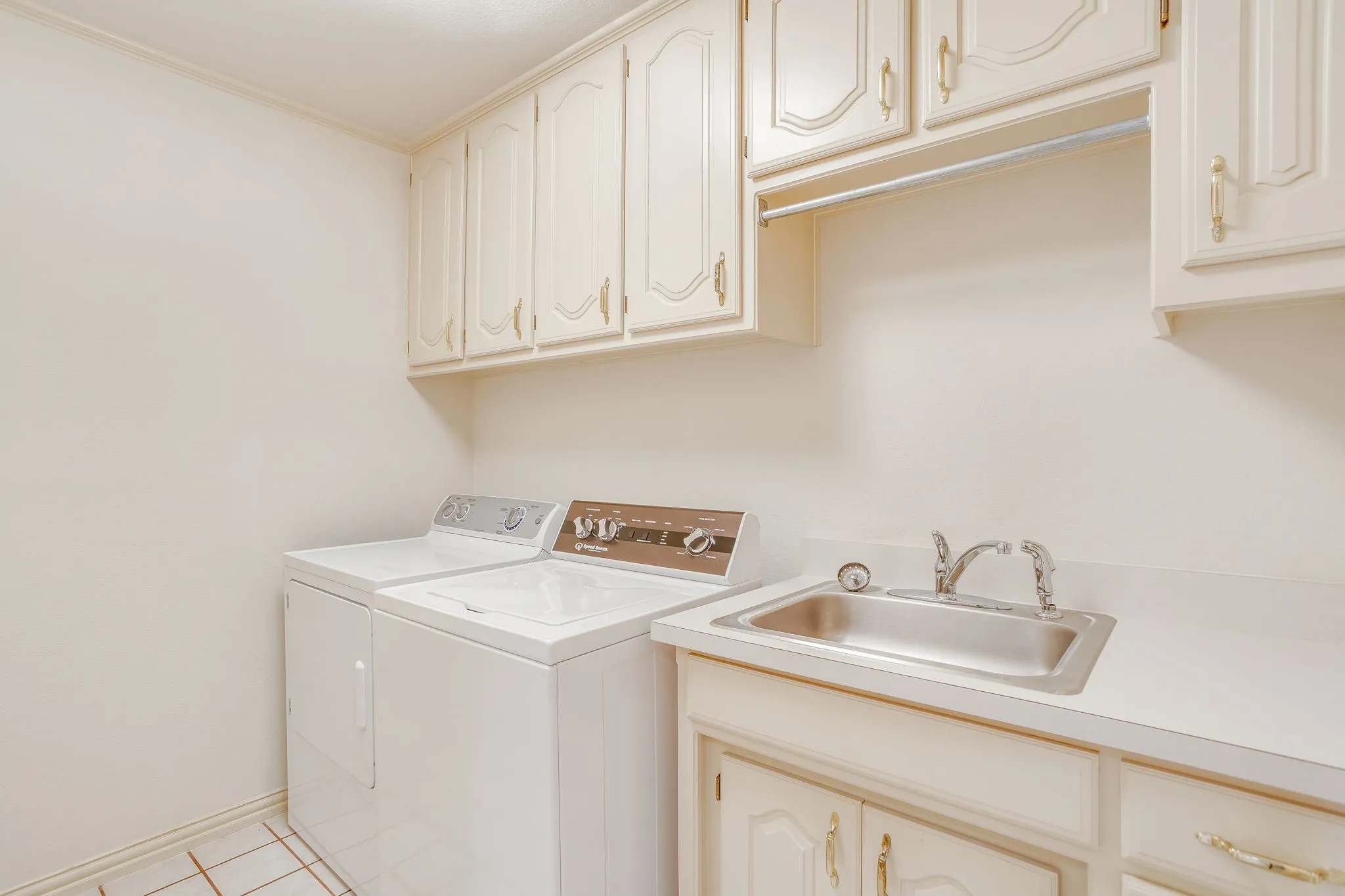Laundry area featuring upper cabinetry, a utility sink with a countertop, and tile flooring