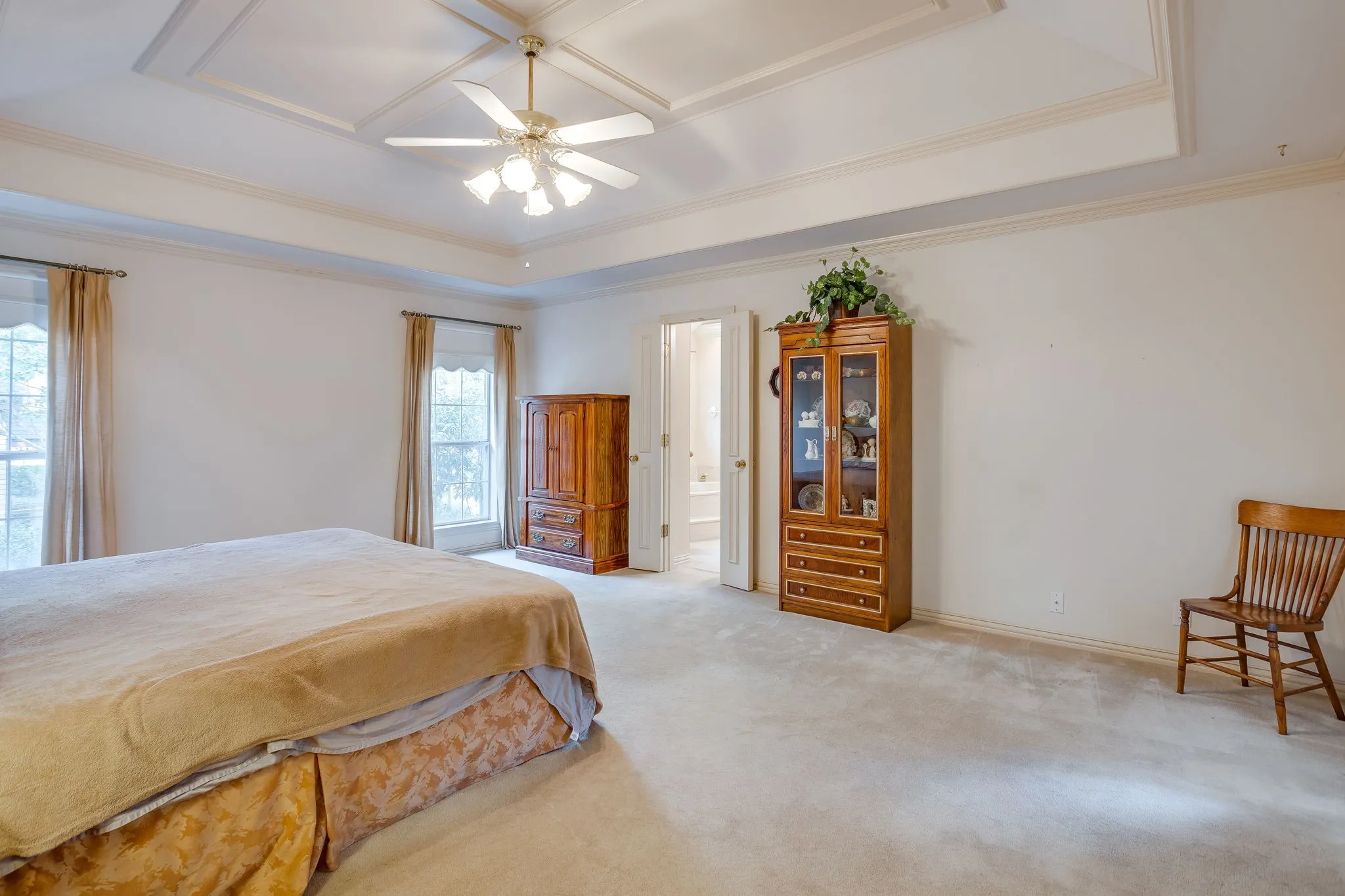 Recessed tray ceiling with crown molding, ceiling fan with integrated lighting, and light-toned carpeting