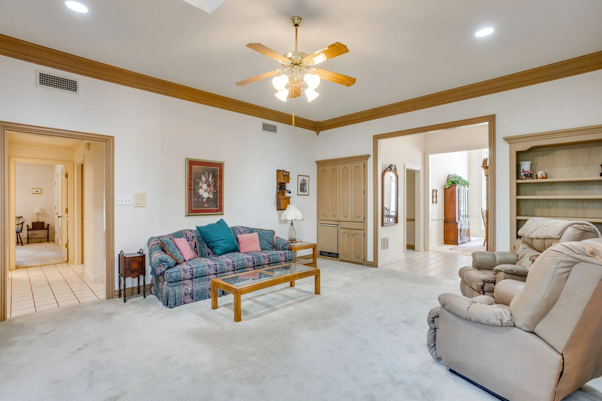 Spacious living area featuring a ceiling fan, recessed lighting, built-in cabinetry, wood-finish trim, and built-in shelving