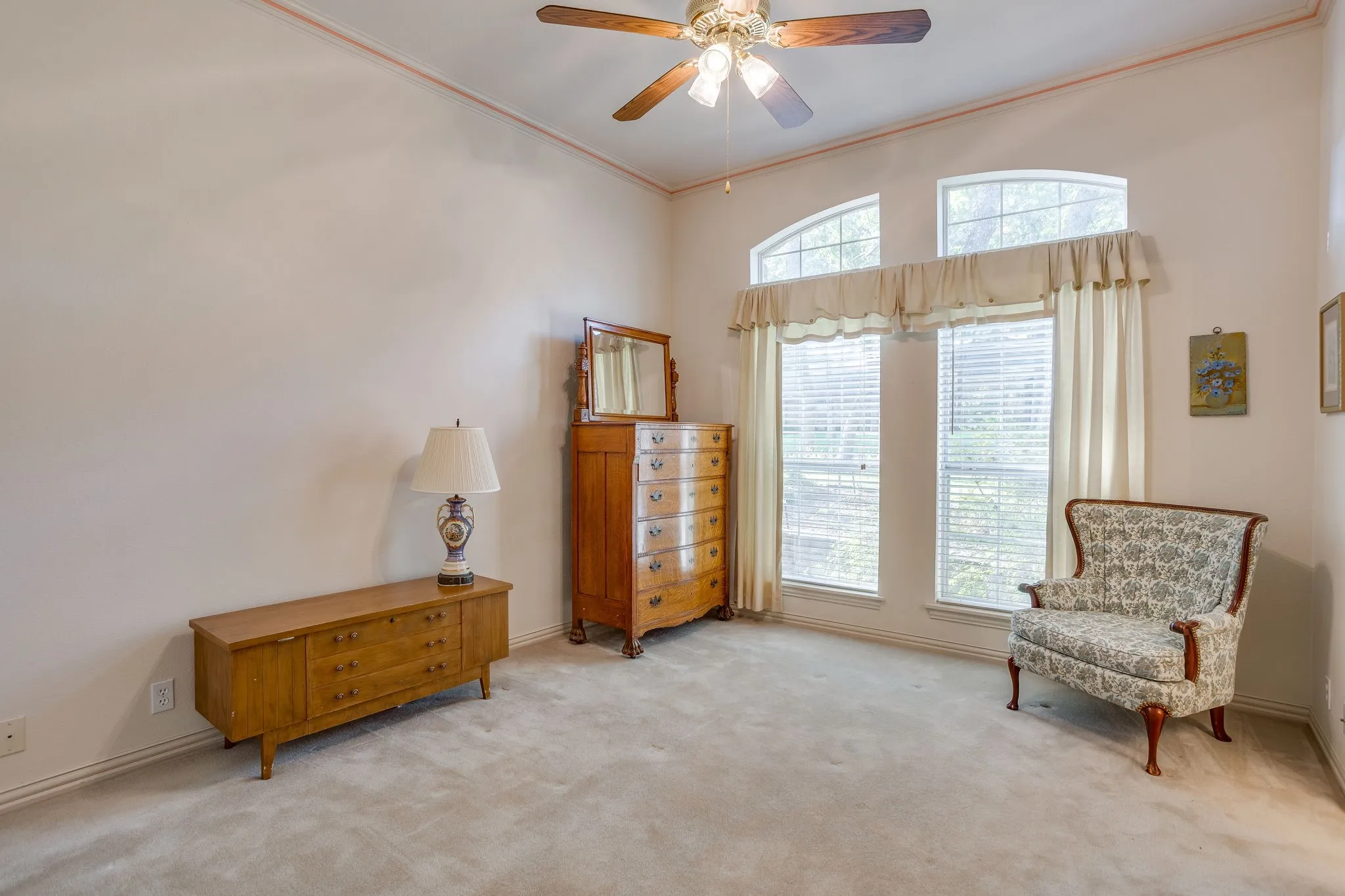 Vaulted ceiling with an attached ceiling fan, large arched windows, and light-toned carpeting