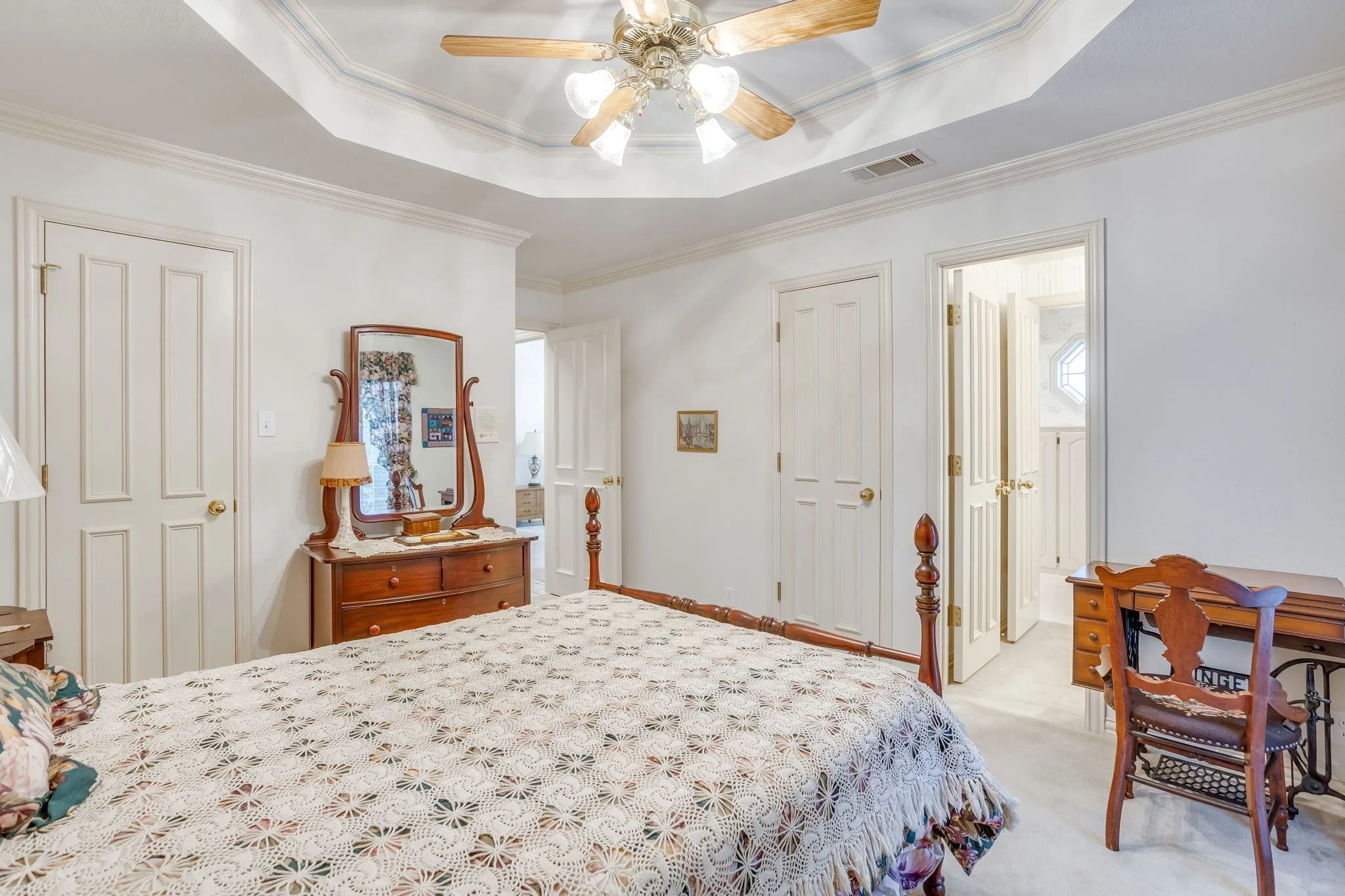 Tray ceiling with crown molding, ceiling fan, and carpet flooring