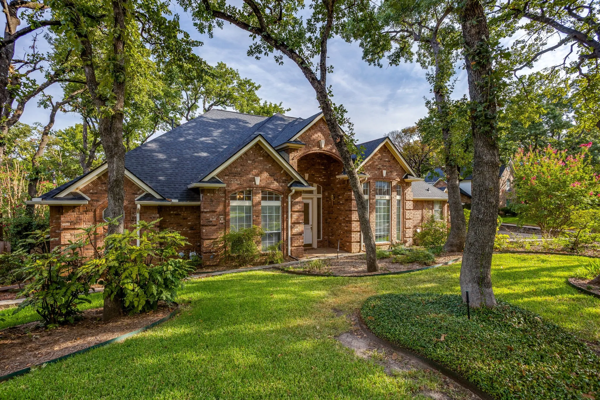 Brick exterior with a dark shingle roof, arched entryway, and multiple windows