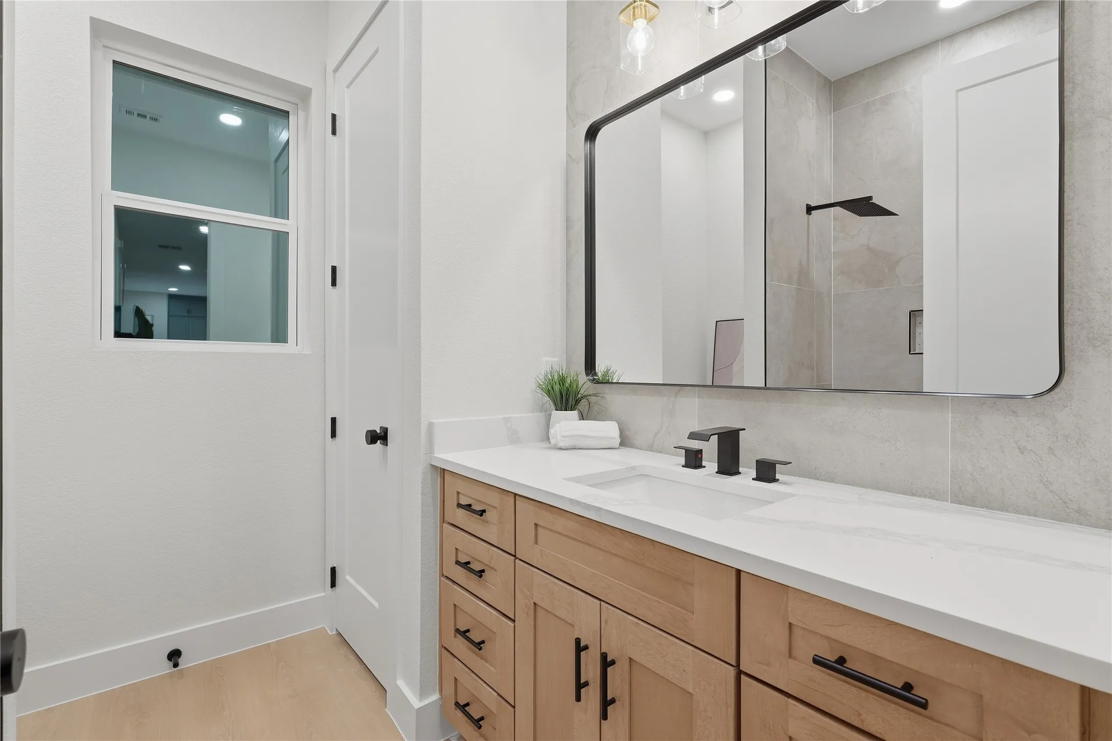 Light wood-finish vanity with ample storage and stone countertop