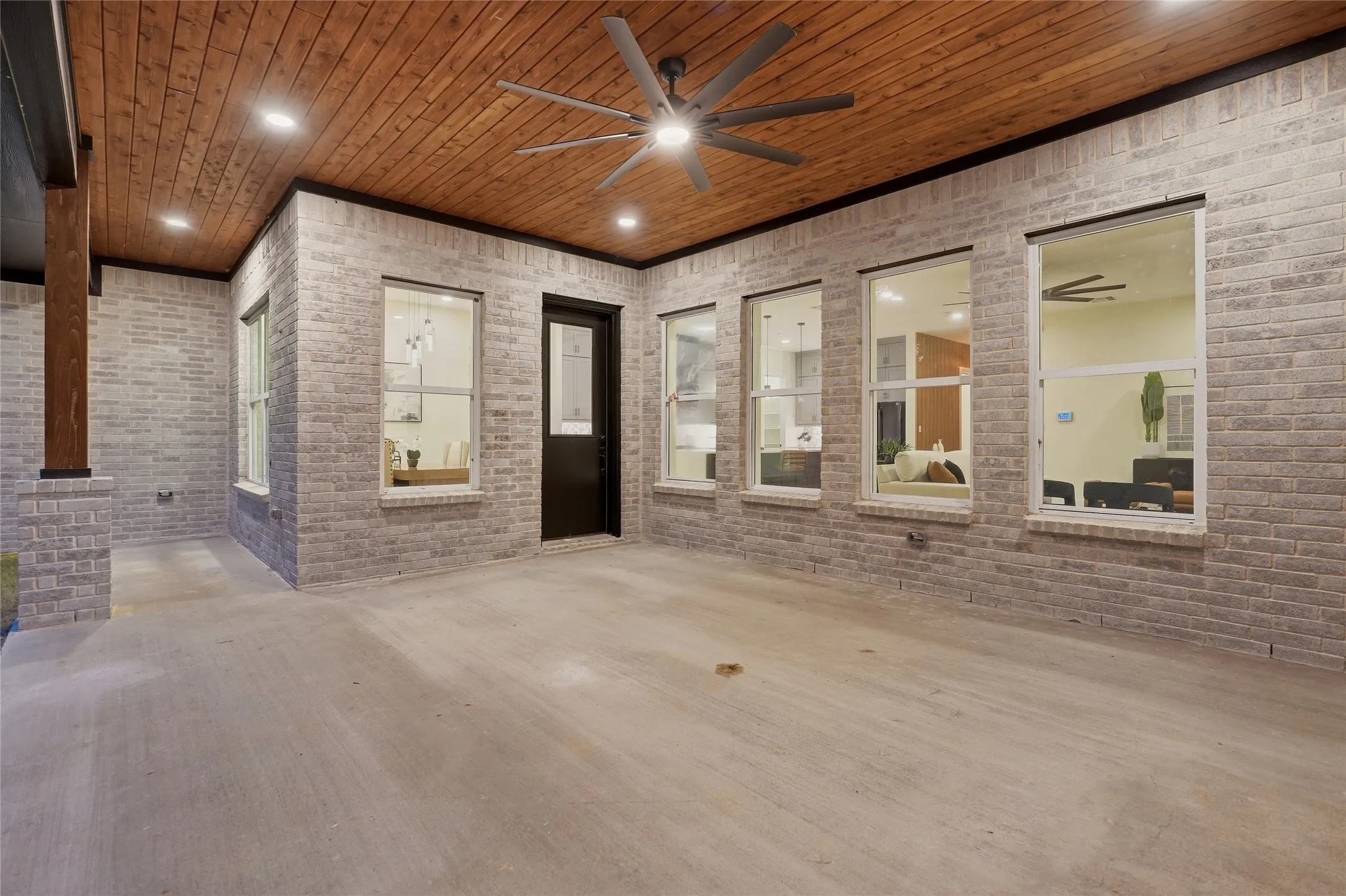 Spacious outdoor patio featuring a wood-panel ceiling, recessed lighting, and a ceiling fan