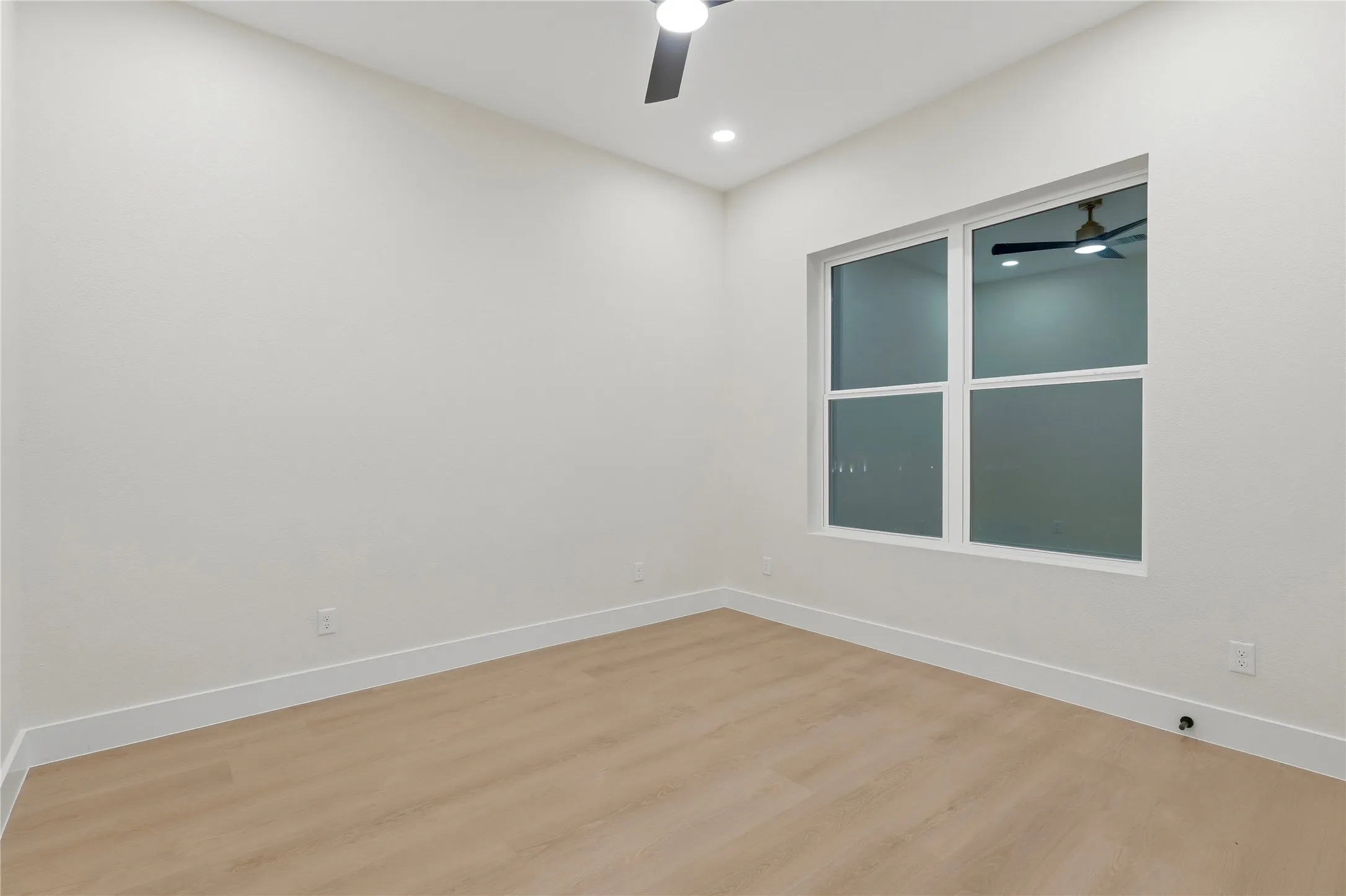 Recessed lighting, wood-finish flooring, ceiling fan, large window, and crisp white trim
