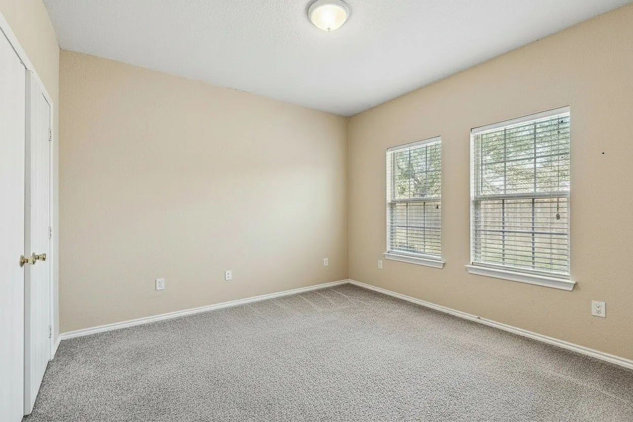 Carpeted bedroom offers a comfortable retreat with neutral finishes and multiple windows providing abundant natural light. | 5931 Robinwood