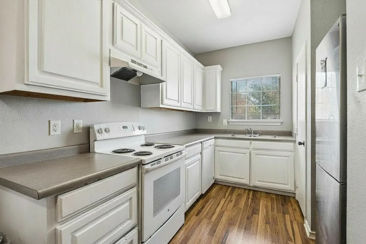 White painted cabinetry provides plentiful kitchen storage alongside laminate countertops and an electric range. | 5933 Robinwood