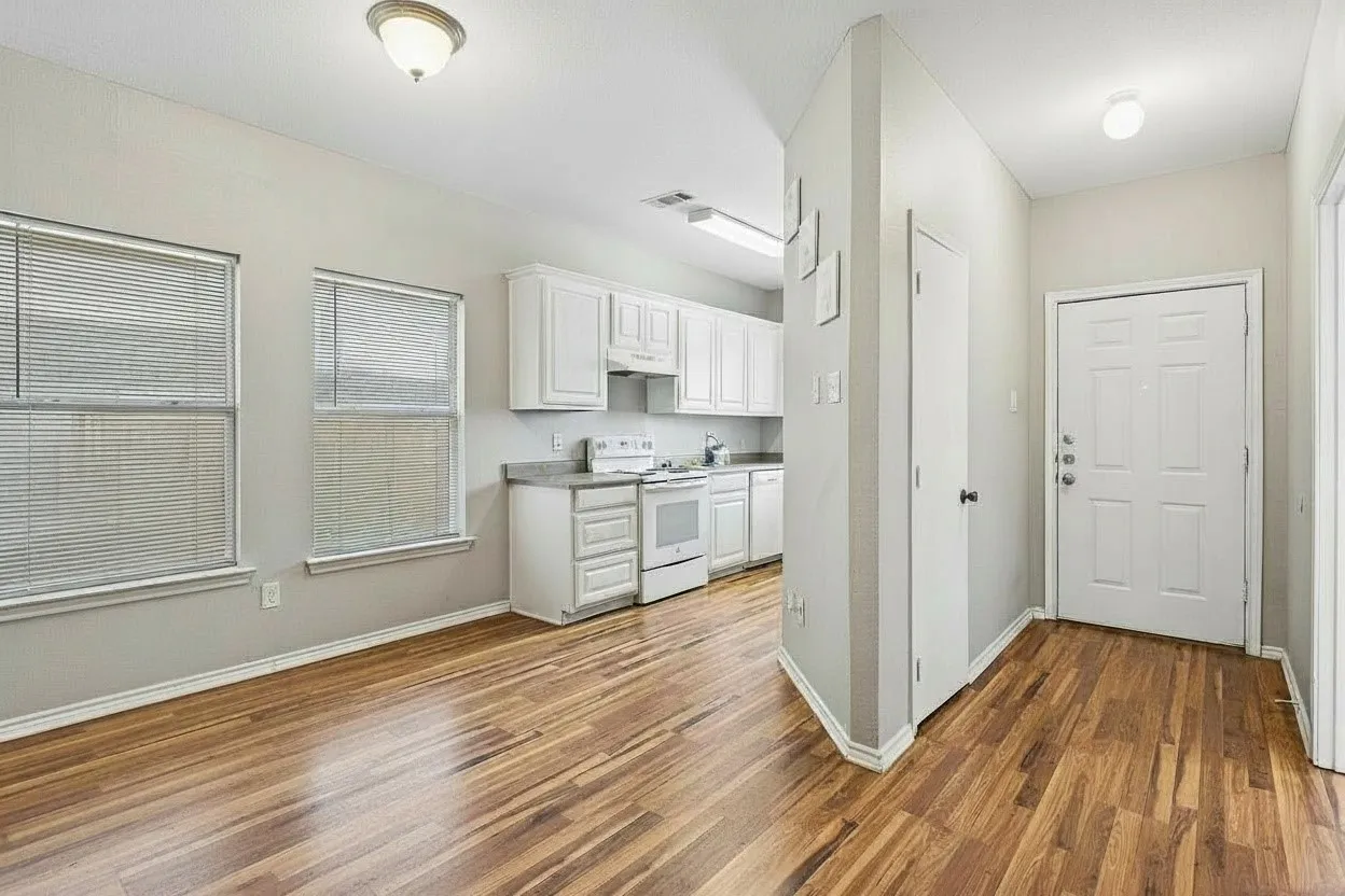 Bright kitchen and dining area pairs white painted cabinetry with wood-look laminate flooring for a clean, neutral presentation. | 5933 Robinwood
