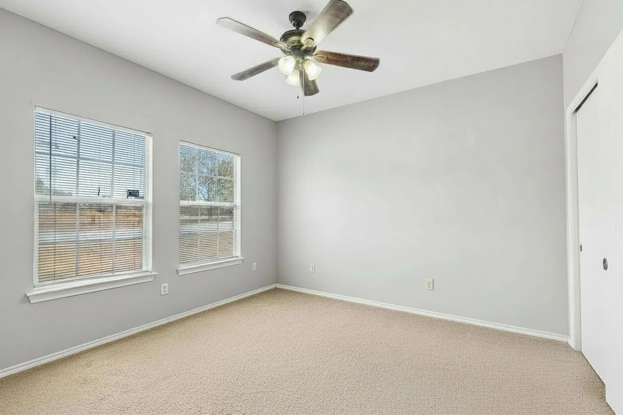 Carpeted bedroom features a ceiling fan, neutral finishes and natural light for a comfortable private space. | 5933 Robinwood