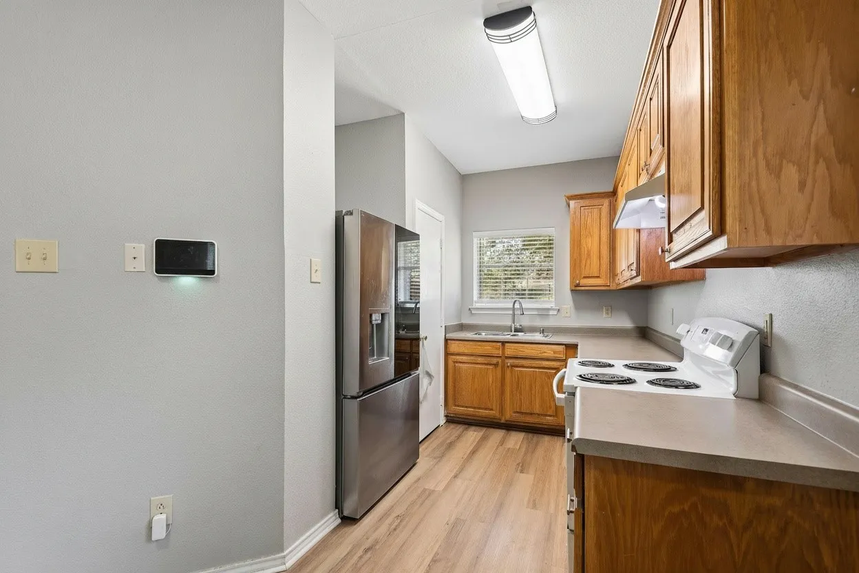 Functional kitchen features stained cabinetry, laminate countertops and an electric range with convenient access to the adjoining dining area. | 5959 Robinwood