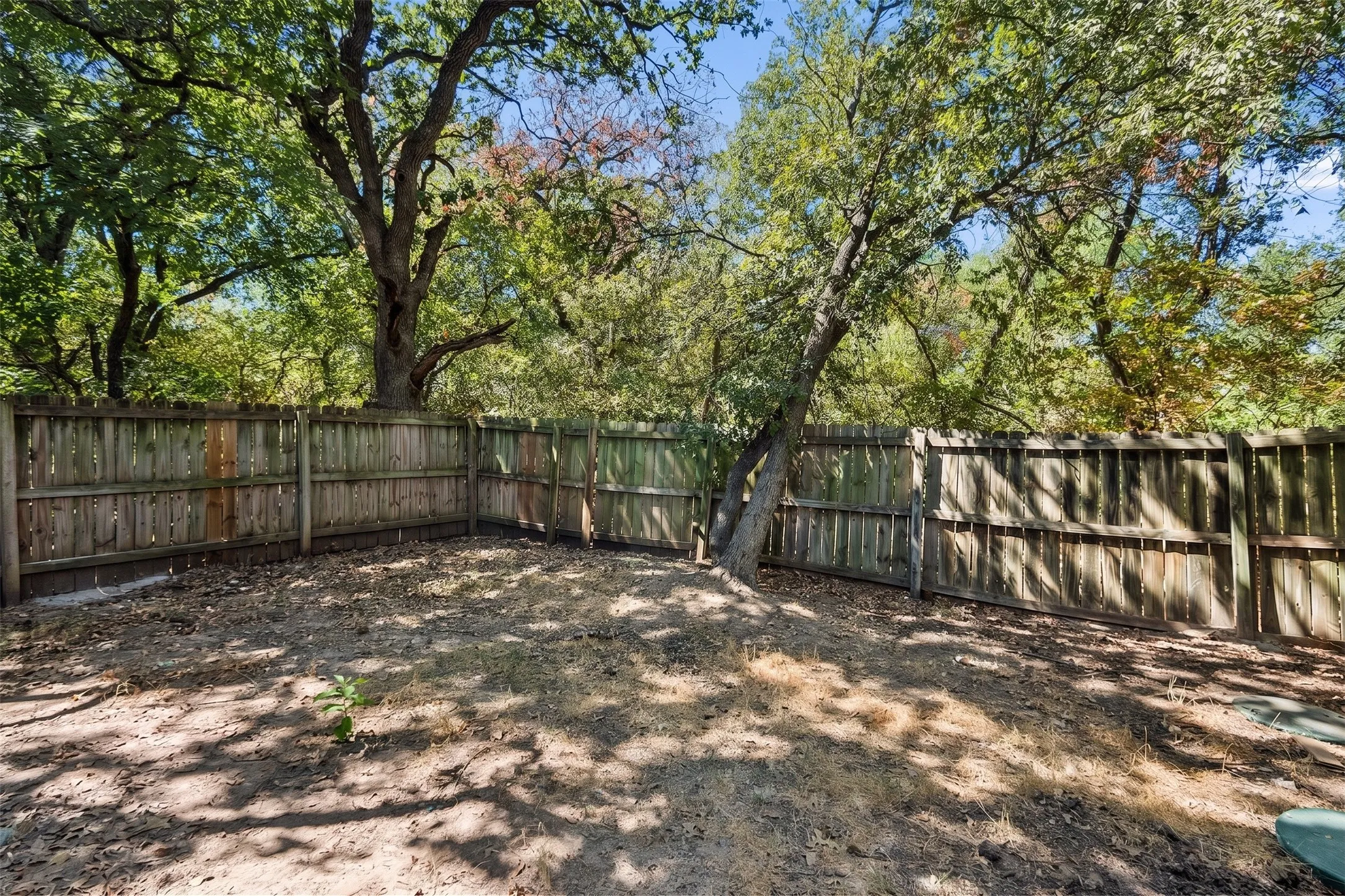 The extended patio creates an inviting spot for outdoor dining, grilling, or unwinding, while mature trees provide welcome shade across the fenced yard. | 5959 Robinwood