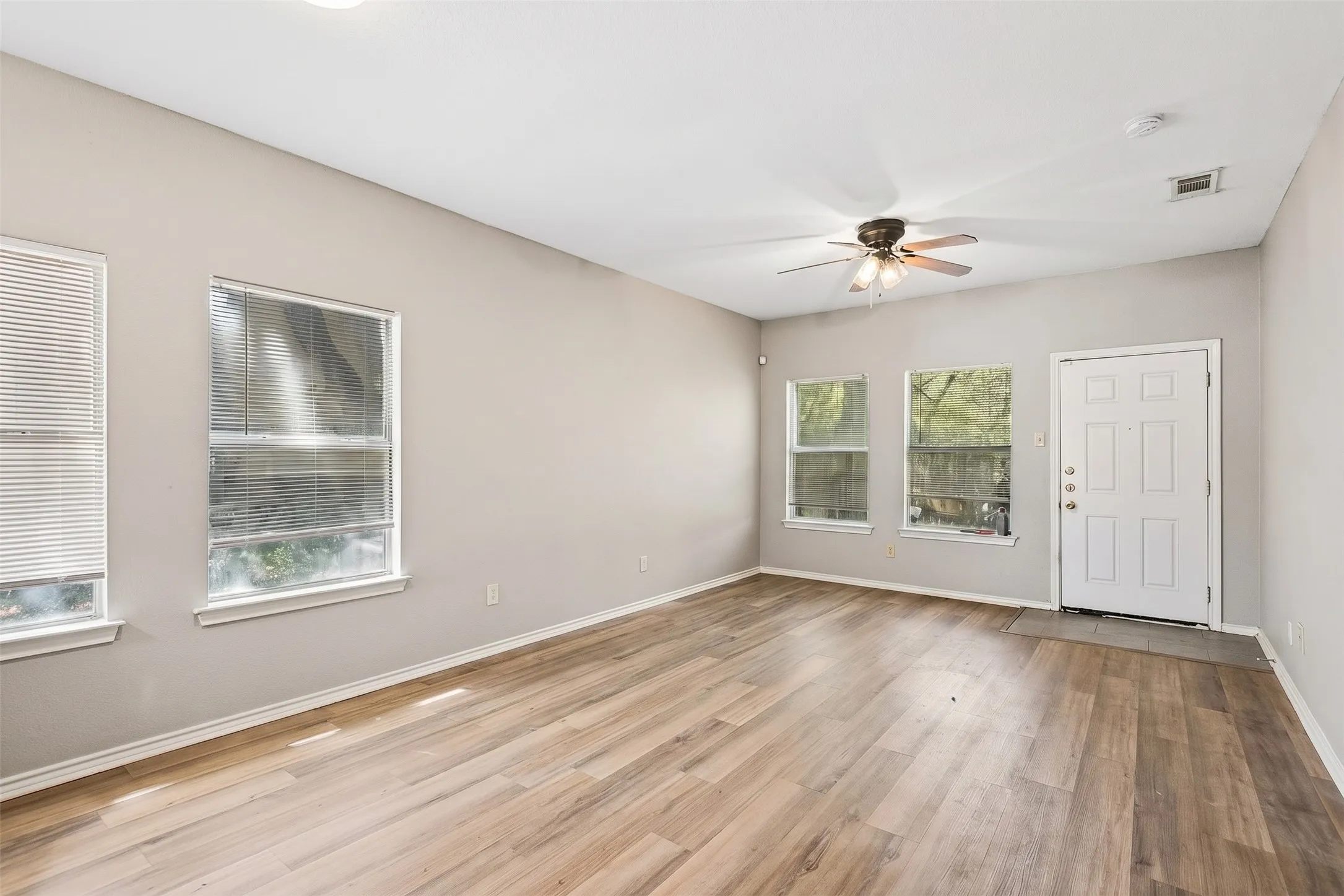 Open, light-filled living room opens to kitchen and features wood-look laminate flooring and a neutral interior. | 5959 Robinwood