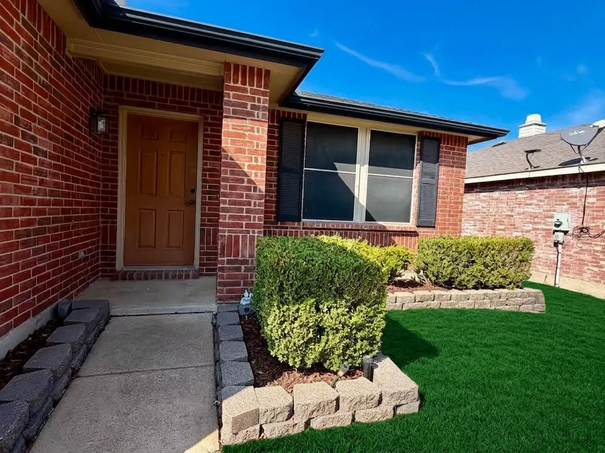 Brick exterior with a covered entry and a paneled front door, staged grass