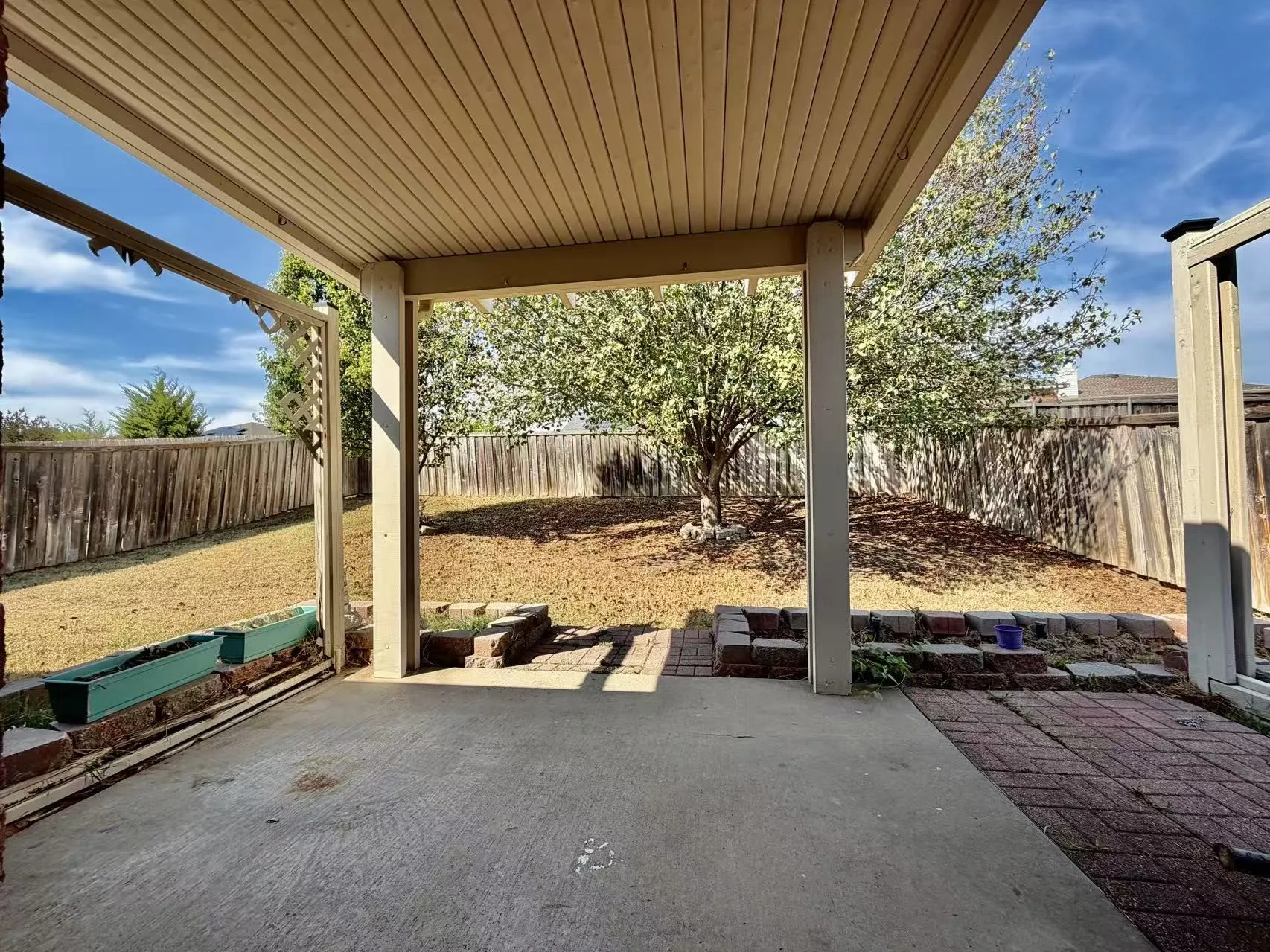 Covered patio with concrete and brick paver flooring, supported by structural posts