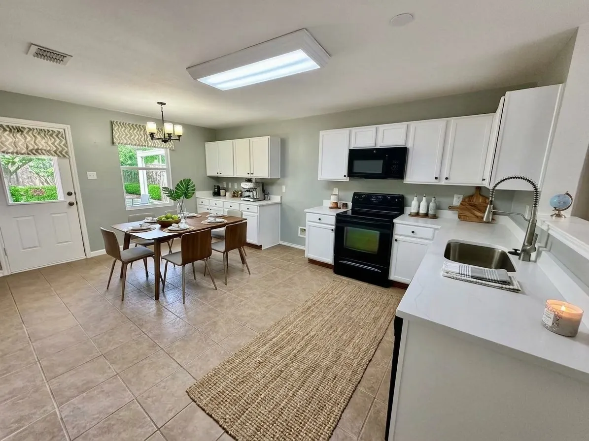 White cabinetry with black hardware, stainless steel sink with a pull-down faucet, black range, and quartez countertops, virtual staged