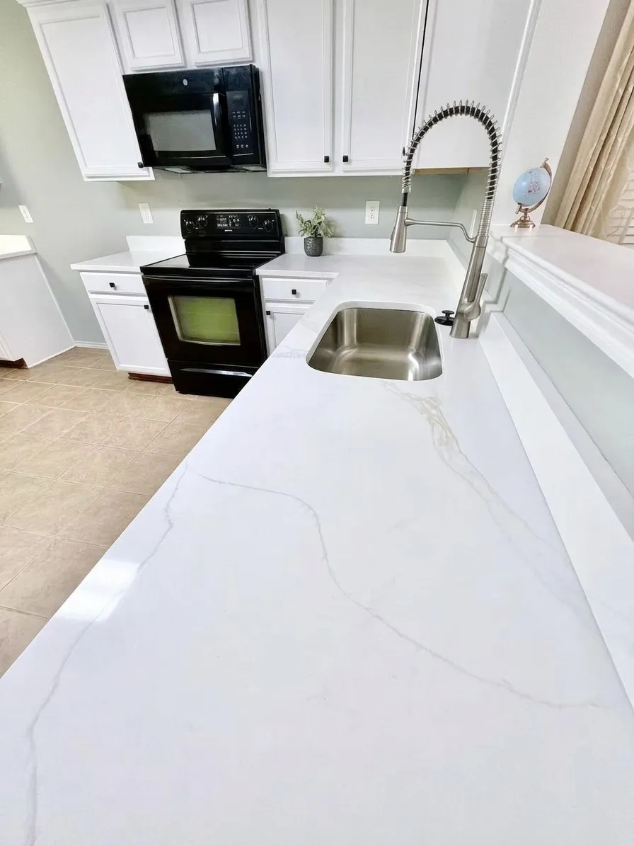 Modern kitchen featuring white cabinetry, black hardware, stainless steel sink, pull-down faucet, and quartez countertops