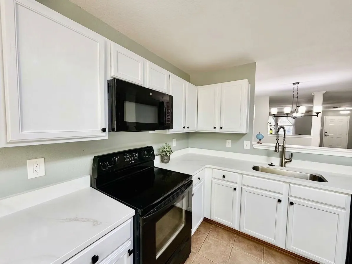 white cabinetry, light-toned countertops, tile flooring, black appliances, and a stainless steel sink with a gooseneck faucet, virtual staged