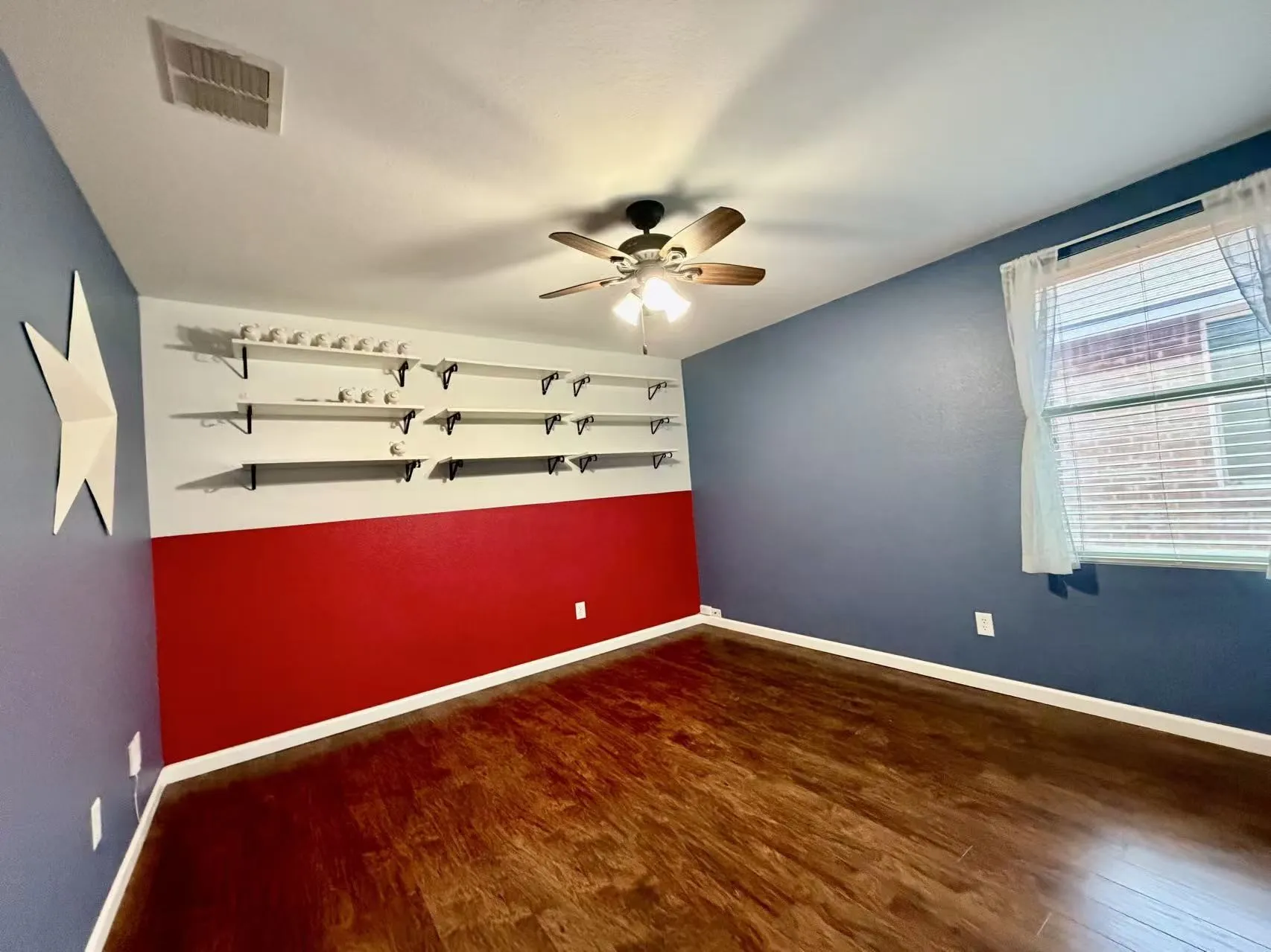 Wood-finish flooring, ceiling fan with integrated lighting, window with blinds, and built-in shelving