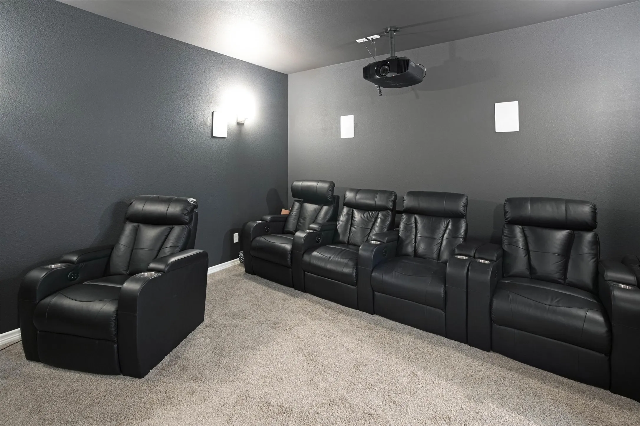 Projector system, ceiling-mounted speakers, wall sconces, and neutral carpet flooring